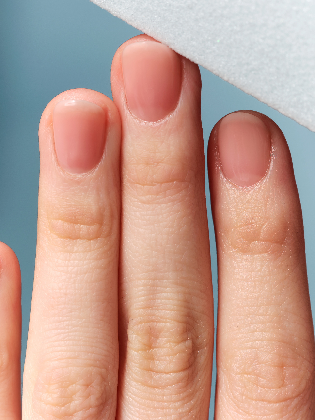 Close-up of bare natural nails with a healthy soft gel overlay finish, buffed and glossy with no added length