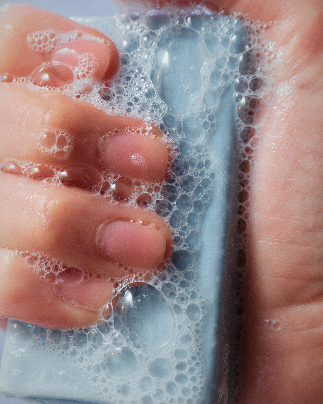 Close-up of hands lathering a bar of soap, waterless cleansing before a manicure